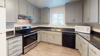 a kitchen with granite counter tops and white cabinets at Gateway, Chico, California